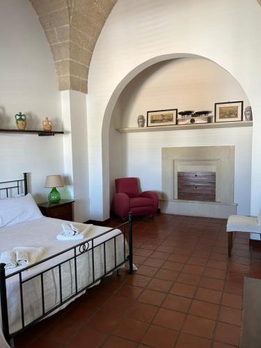 a bedroom with a bed and a chair and a fireplace at B&B Palazzo Giordano Luxury Rooms in Squinzano