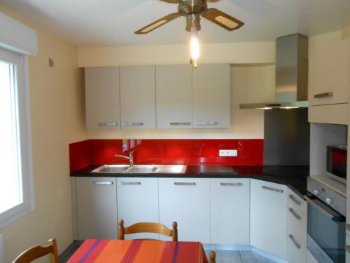 Il comprend une cuisine avec des placards blancs et un ventilateur de plafond. dans l'établissement MAISON ENTRE MER et CAMPAGNE, à Saint-Alban