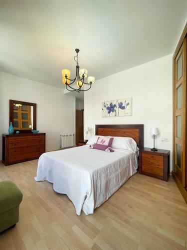 a bedroom with a large white bed and a chandelier at Casa Príncipe 12 in Cambados