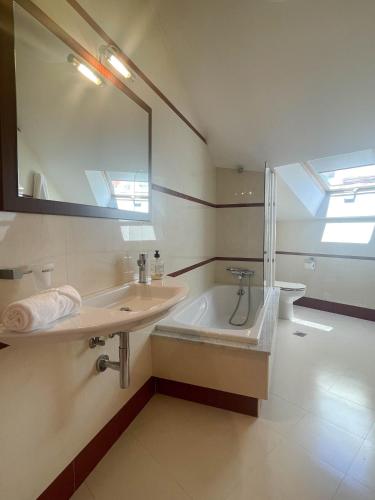 a bathroom with a sink and a tub and a mirror at Casa Príncipe 12 in Cambados