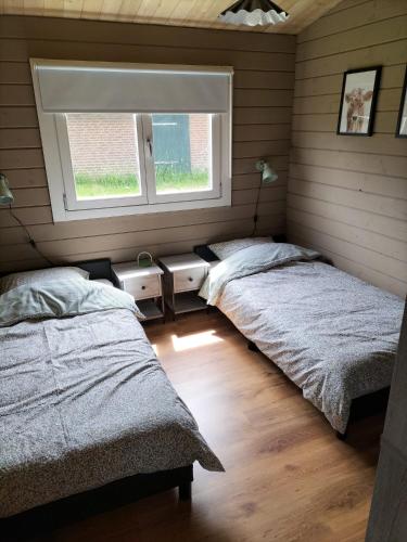 two beds in a room with a window at vakantiehuis kruisvennenhoeve in Ospel
