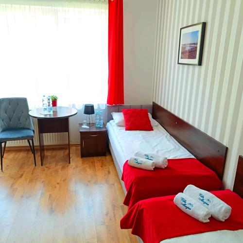 two beds in a room with a table and a chair at Villa Magna in Gdynia