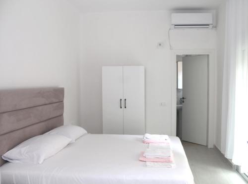 a white bedroom with a large bed with white sheets at Vila Jovani in Sarandë