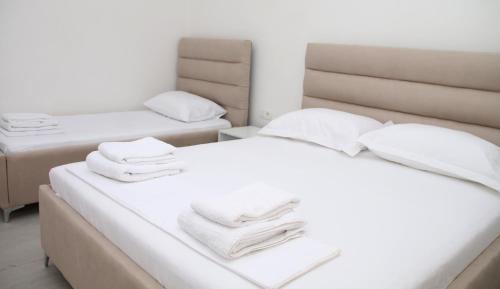 two beds in a room with white towels on them at Vila Jovani in Sarandë