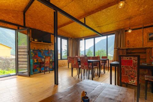 ein Esszimmer mit einem Tisch und einigen Fenstern in der Unterkunft Kazbegi Cottages in Kazbegi