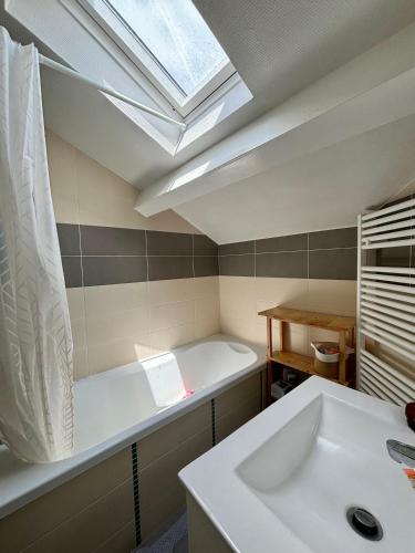 une salle de bain avec un lavabo blanc et une lucarne dans l'établissement Le cocon, à Aurillac