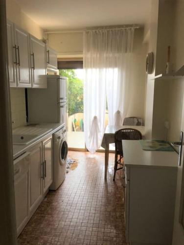 une cuisine avec une fenêtre et une table et une cuisine avec une machine à laver dans l'établissement Bright 70m2 2-room apartment,garden,facing the sea, à Menton