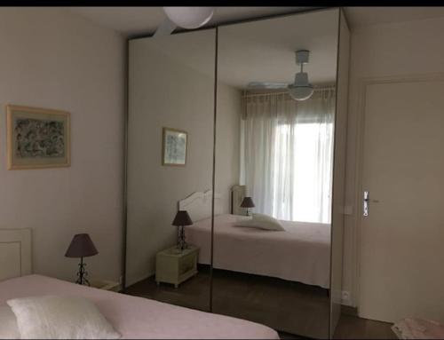 une chambre avec deux lits et un miroir dans l'établissement Bright 70m2 2-room apartment,garden,facing the sea, à Menton
