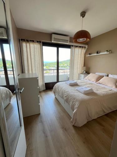 Un dormitorio con una cama grande y grandes ventanales. en T2 centre ville avec vue imprenable, en Chambéry