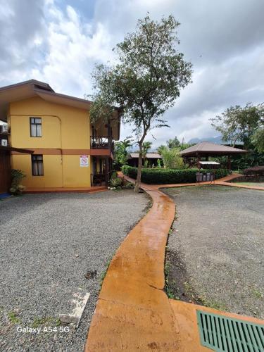 a road in front of a building with a tree at Hotel Iris Arenal in Fortuna