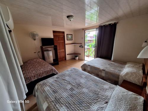a hotel room with two beds and a window at Hotel Iris Arenal in Fortuna