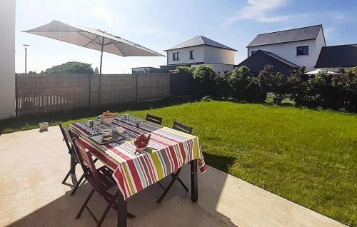 a table with a striped table cloth and an umbrella at Maison Moderne Proche Plage in Saint-Coulomb