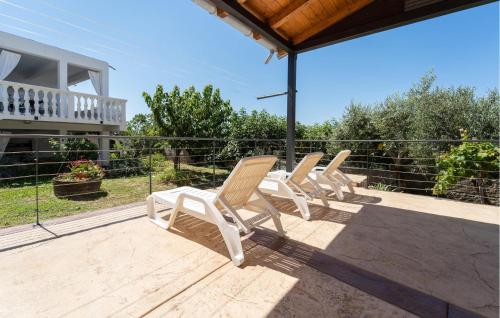 a row of white chairs sitting on a patio at 2 Bedroom Lovely Apartment In Rtina in Rtina