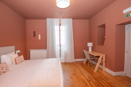 a bedroom with a bed and a desk and a window at Palácio dos Marqueses in Mafra