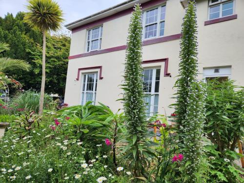 a garden in front of a house with flowers at Rose Court Holiday Apartments in Torquay