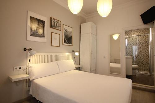 a bedroom with a white bed and a bathroom at Las Atarazanas - Design Hostal in Seville