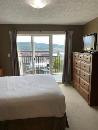 a bedroom with a bed and a television and a balcony at Race Rocks Townhouse - Sooke in Sooke