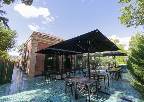a patio with tables and chairs and umbrellas at Maison de charme avec Piscine intérieure & Jardin in Vanves