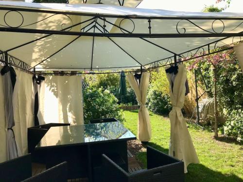 a tent with a glass table in a yard at Maison de charme avec Piscine intérieure & Jardin in Vanves