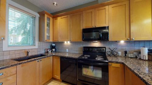 a kitchen with wooden cabinets and a black stove top oven at Sooke Harbour Getaway in Sooke