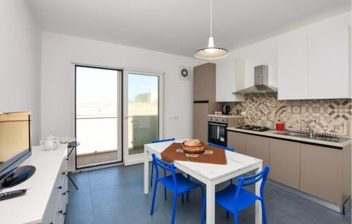 a kitchen with a white table and blue chairs at Cozy Apartment In Santa Croce Camerina in Santa Croce Camerina