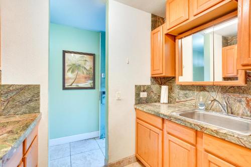a kitchen with wooden cabinets and a sink at Downtown Kailua-Kona Escape Steps to Ocean! in Kailua-Kona