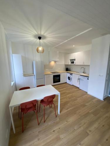 - une cuisine blanche avec une table blanche et des chaises rouges dans l'établissement Le Republic, à Capdenac-Gare