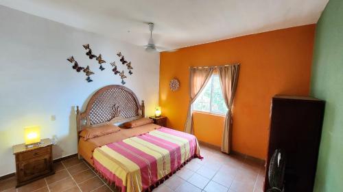a bedroom with a bed with an orange wall at Villas Santa Cecilia Villa GeeGee en Yelapa in Yelapa
