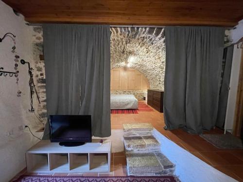 a living room with a bed and a room with a television at Τελωνείο Βαμβακούς in Vamvakoú