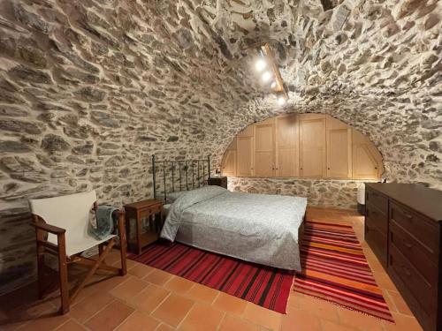 a bedroom with a bed and a stone wall at Τελωνείο Βαμβακούς in Vamvakoú