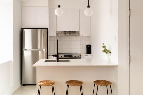 a kitchen with a stainless steel refrigerator and two stools at Maison Rasco by Luxury In Transit in Montréal