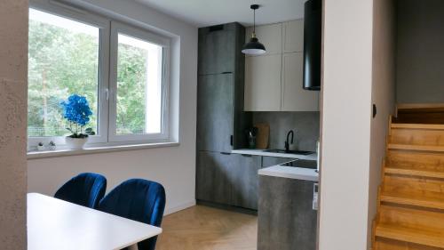 a kitchen with a white table and blue chairs at Domy Leśne Szumy na Roztoczu in Zwierzyniec