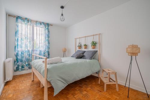 une chambre avec un lit dans une pièce blanche dans l'établissement Le Jardin Secret, à Seyssinet-Pariset