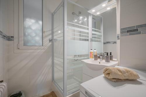 ein weißes Badezimmer mit Dusche und Waschbecken in der Unterkunft Le Jardin Secret in Seyssinet-Pariset