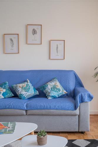 - un canapé bleu avec deux oreillers dans le salon dans l'établissement Le Jardin Secret, à Seyssinet-Pariset