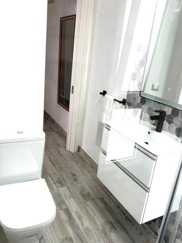 a white bathroom with a toilet and a sink at Casa Gary in Caleta de Caballo