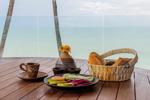 a wooden table with a plate of vegetables and a basket at Carmel Taíba Exclusive Resort in Taíba