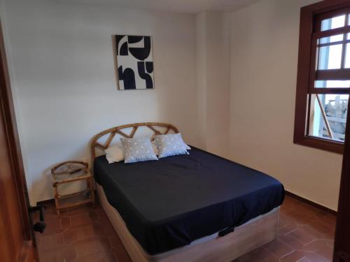 a bedroom with a bed with blue sheets and a window at La Casa del Sol in La Eliana