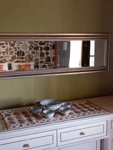 a mirror on top of a dresser with bowls on it at Stone and Serenity Cottage in Pilion