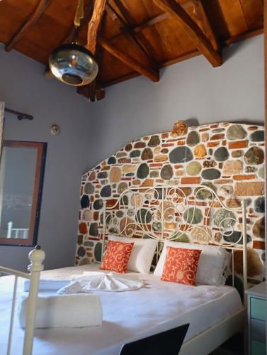a bed in a room with a stone wall at Stone and Serenity Cottage in Pilion