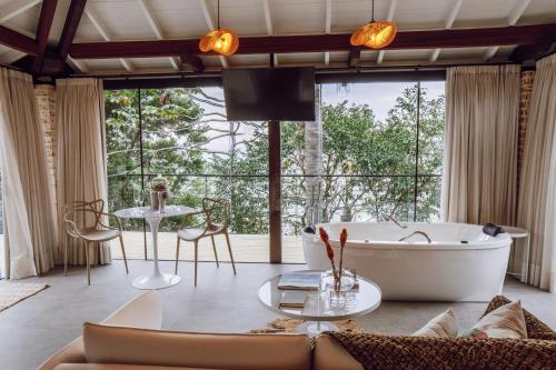 a living room with a tub and a large window at Naatooh Guest Houses in Florianópolis
