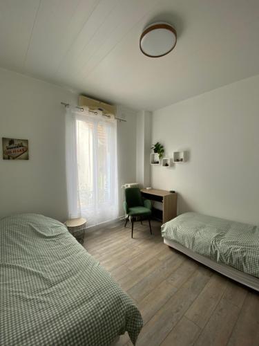 - une chambre avec 2 lits et un bureau avec une chaise dans l'établissement Appartement de charme climatisé à Bagneux, à Bagneux