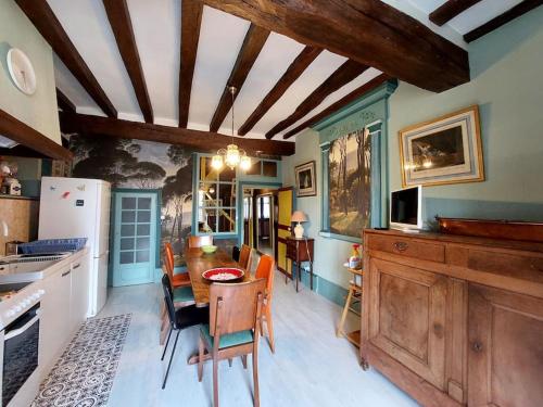 une cuisine avec une table, des chaises et un réfrigérateur dans l'établissement Chez Koryne, à Loudun