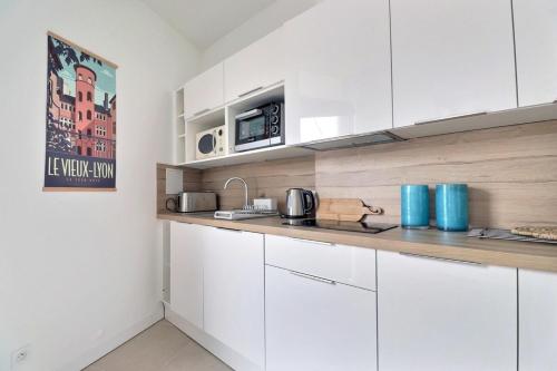 une cuisine avec des armoires blanches et un comptoir dans l'établissement Le Charpennes - Beautiful T1 Apartment - Villeurbanne, à Villeurbanne