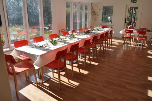 a long table with red chairs in a room with windows at långstorp höör huvudbyggnad v flygel in Höör