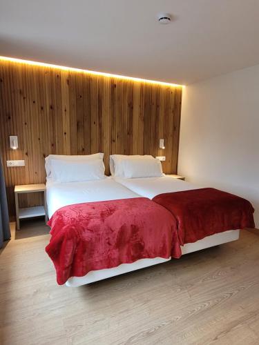 a bedroom with a large white bed with a red blanket at La Mira de Gredos in Hoyos del Espino