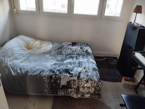 une chambre avec un lit avec une couverture dessus dans l'établissement Appartement calme près des métros et des JO 2024, à Saint-Denis