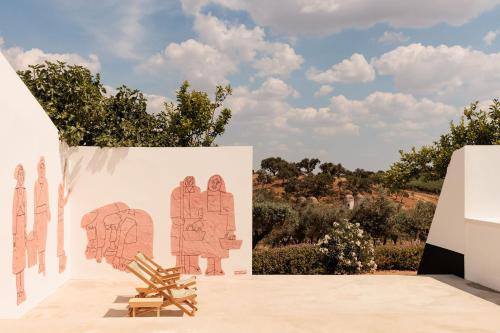 a wooden bench sits next to a wall with a mural at O Val farmhouse in Monforte