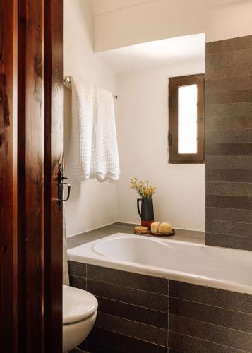 a bathroom with a tub and a toilet and a sink at O Val farmhouse in Monforte