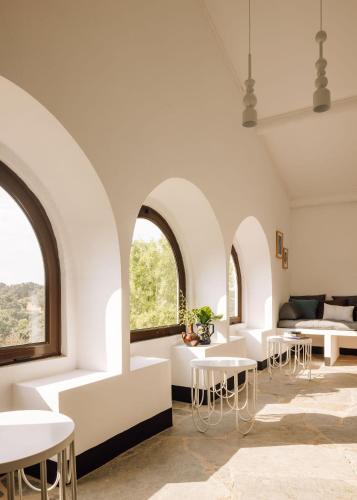 a room with white tables and chairs and windows at O Val farmhouse in Monforte
